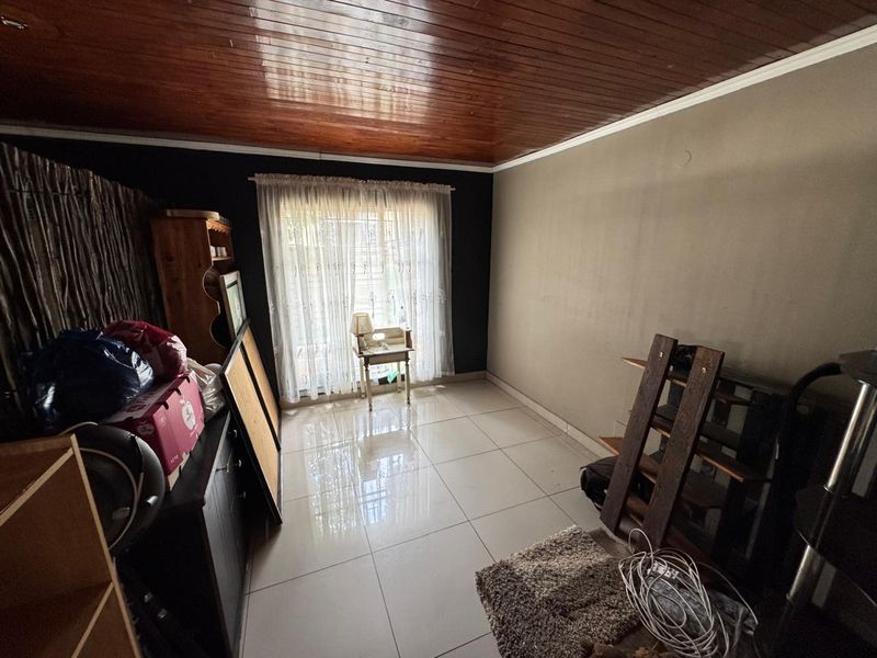 A living room featuring polished floor tiles and a timber-paneled ceiling, providing a neutral base for future interior design updates.