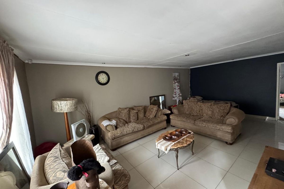 A spacious living room featuring large format floor tiles and a neutral color palette with a dark accent wall.