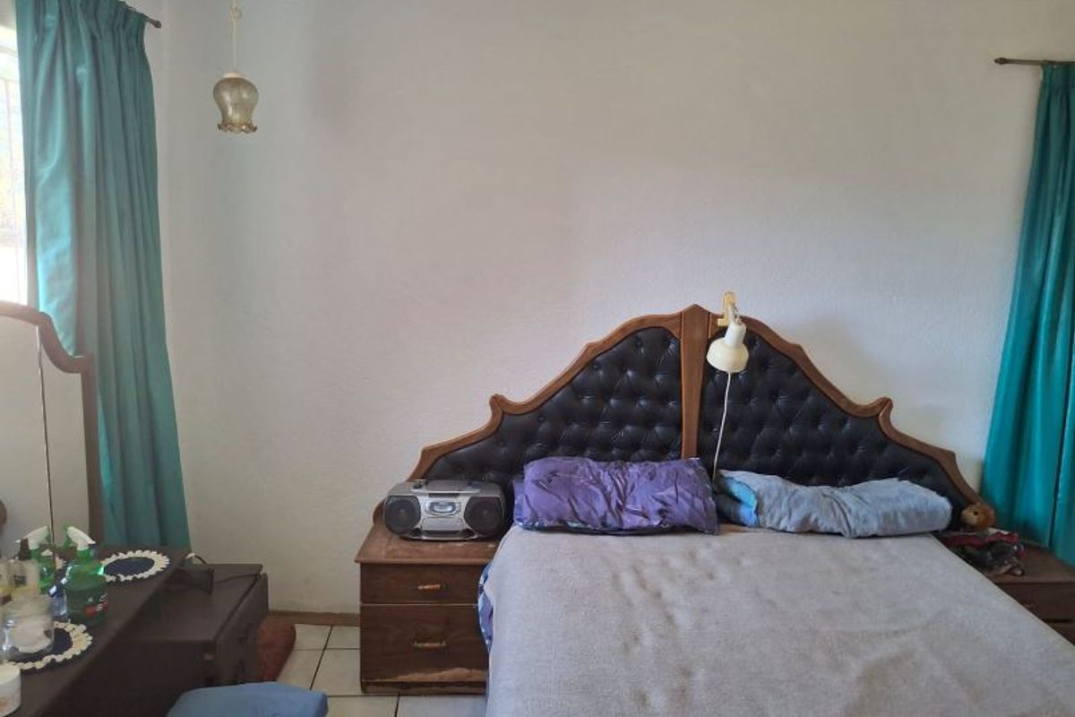 A bedroom featuring tiled flooring and a built-in headboard, offering a functional space ready for cosmetic updates and modernization.
