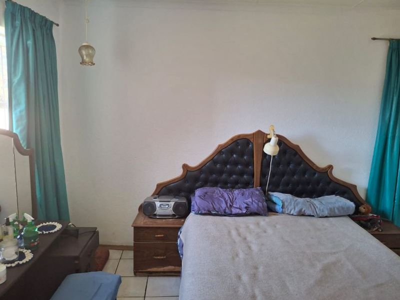 A bedroom featuring tiled flooring and a built-in headboard, offering a functional space ready for cosmetic updates and modernization.