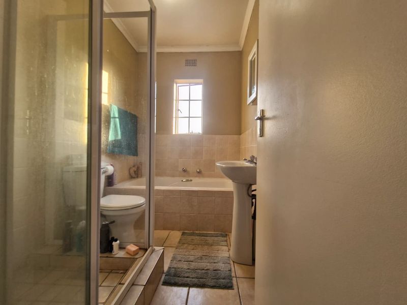 A functional bathroom featuring a shower enclosure, pedestal basin, and a built-in bathtub with tiled surround and flooring.