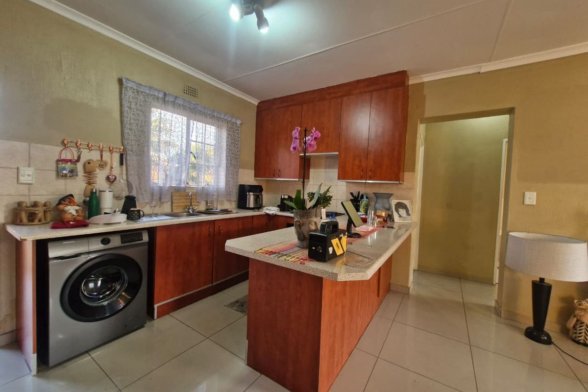 A functional kitchen featuring wood-look cabinetry, laminate countertops, tiled flooring, and an integrated washing machine space.