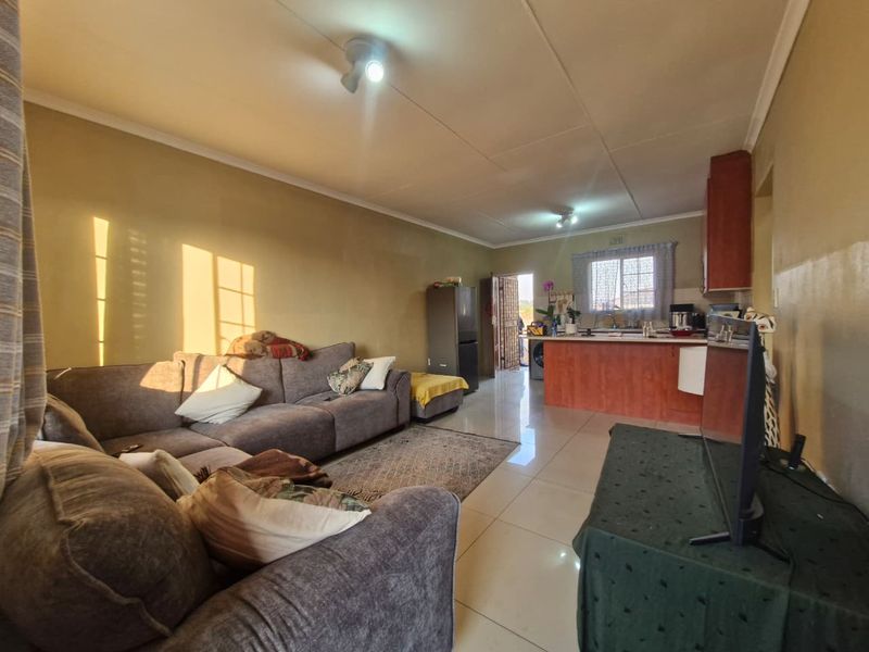 Open-plan living area featuring tiled floors and a functional kitchen with built-in cabinetry, providing a versatile space for daily living.