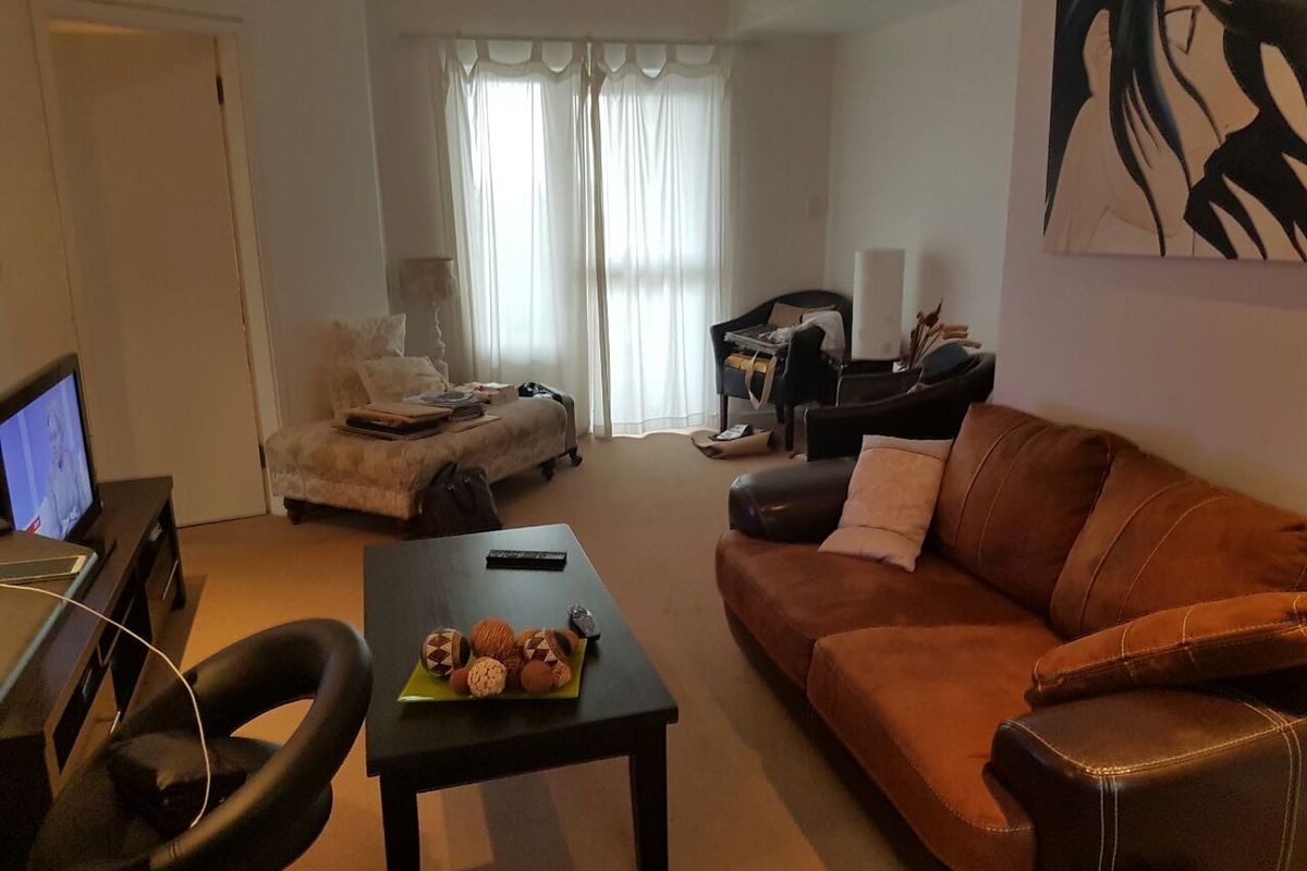 A living room area featuring carpeted flooring and a sliding glass door providing natural light.