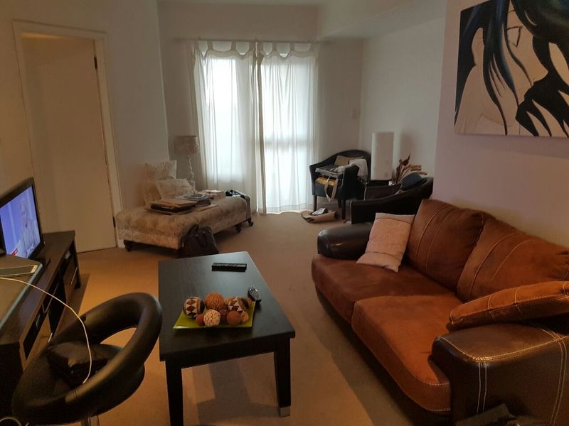 A living room area featuring carpeted flooring and a sliding glass door providing natural light.