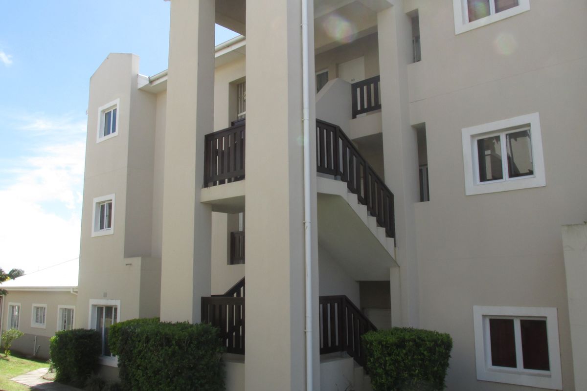 Exterior view of an apartment building featuring a multi-level staircase with dark timber balustrades and neutral-toned facade finishes.