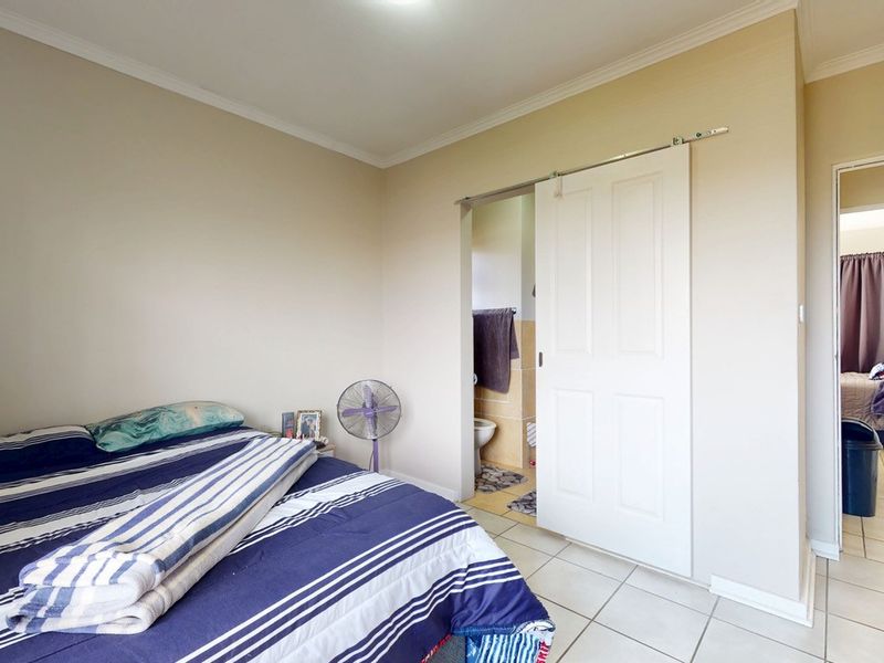 A bedroom featuring tiled flooring, coved ceilings, and a sliding barn door providing access to an en-suite bathroom.