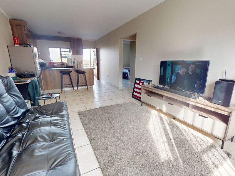 Open plan living area featuring tiled flooring and a functional kitchen with breakfast bar island, connecting to the main living space.