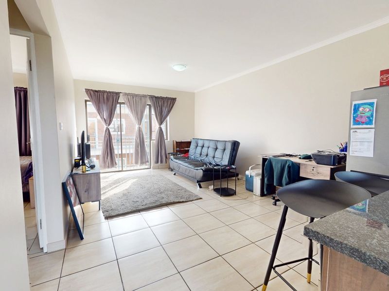 Open-plan living area featuring tiled flooring, a granite kitchen countertop, and a sliding glass door leading to an outdoor space.