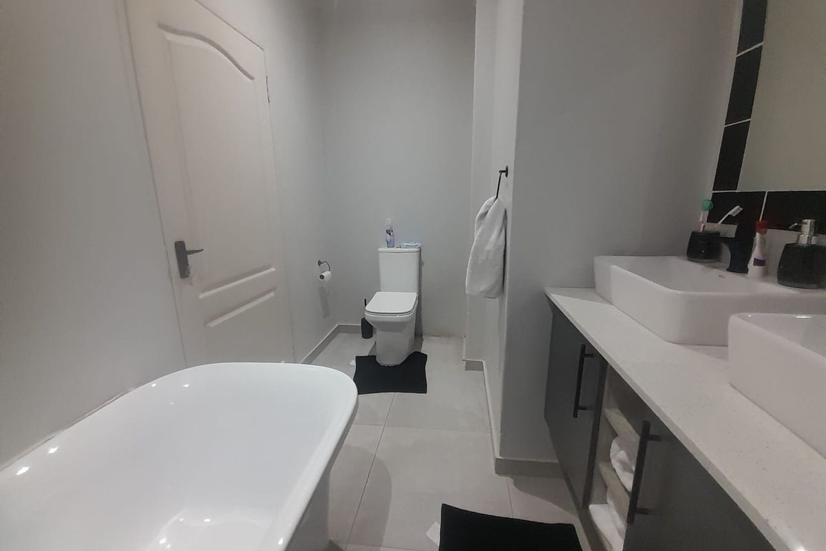 Modern bathroom featuring a freestanding bathtub, double vanity with vessel sinks, and contemporary cabinetry in a clean, neutral finish.