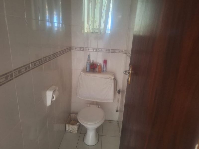 A compact guest bathroom featuring tiled walls and flooring with a standard toilet fixture.