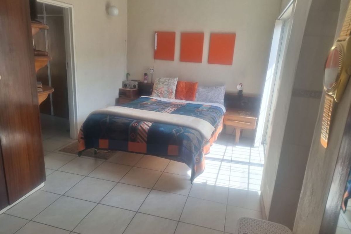A bedroom featuring tiled flooring, built-in cupboards, and a sliding door providing natural light access.