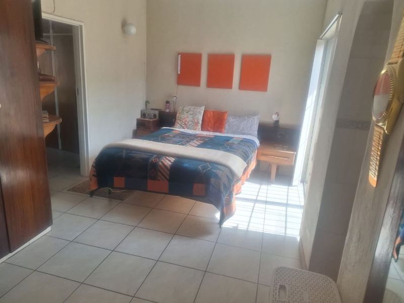 A bedroom featuring tiled flooring, built-in cupboards, and a sliding door providing natural light access.