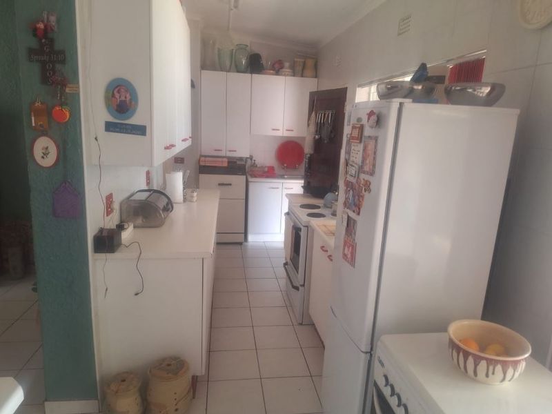 A functional galley-style kitchen featuring white cabinetry, tiled flooring, and built-in cooking appliances, offering a practical layout for daily meal preparation.