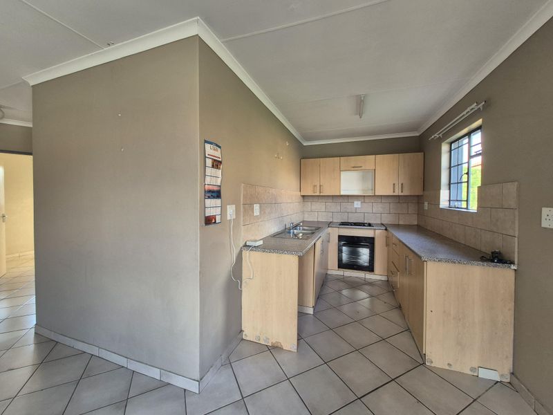 A functional kitchen featuring light wood cabinetry, granite-look laminate countertops, a built-in oven, gas hob, and neutral ceramic floor tiles.