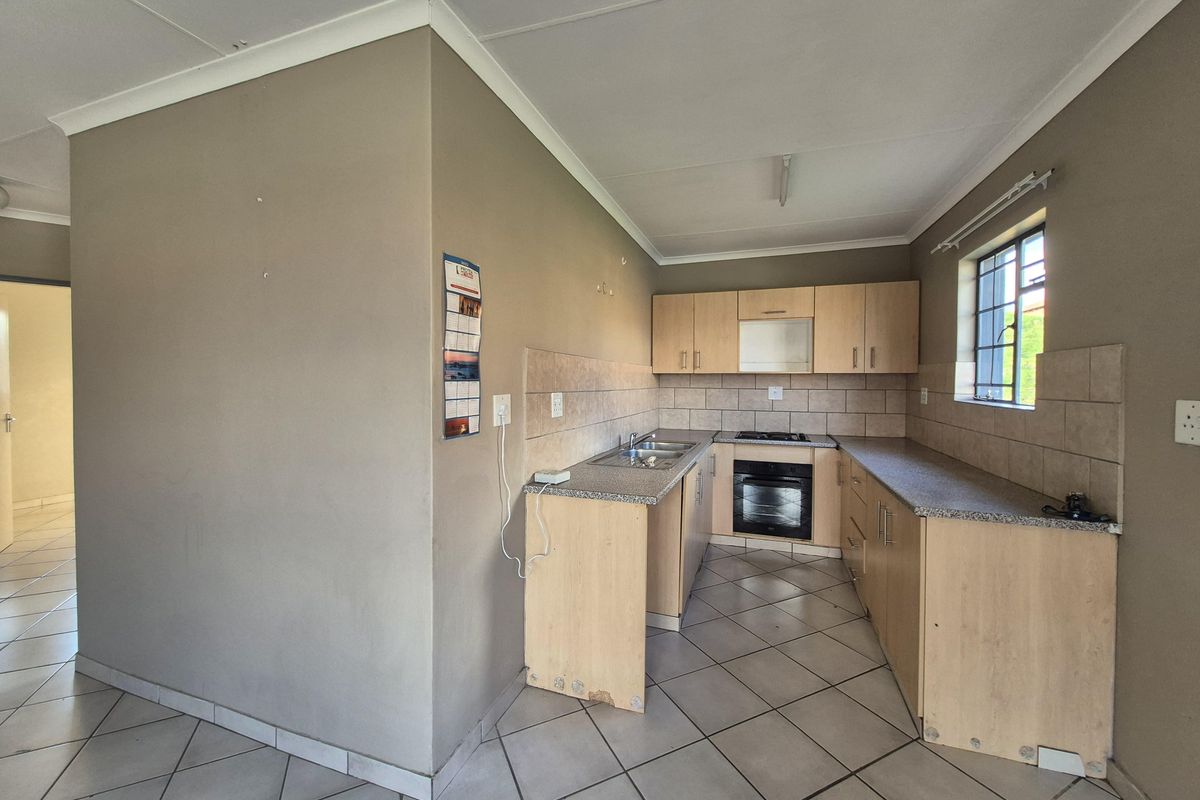 A functional kitchen featuring light wood cabinetry, granite-look laminate countertops, a built-in oven, gas hob, and neutral ceramic floor tiles.
