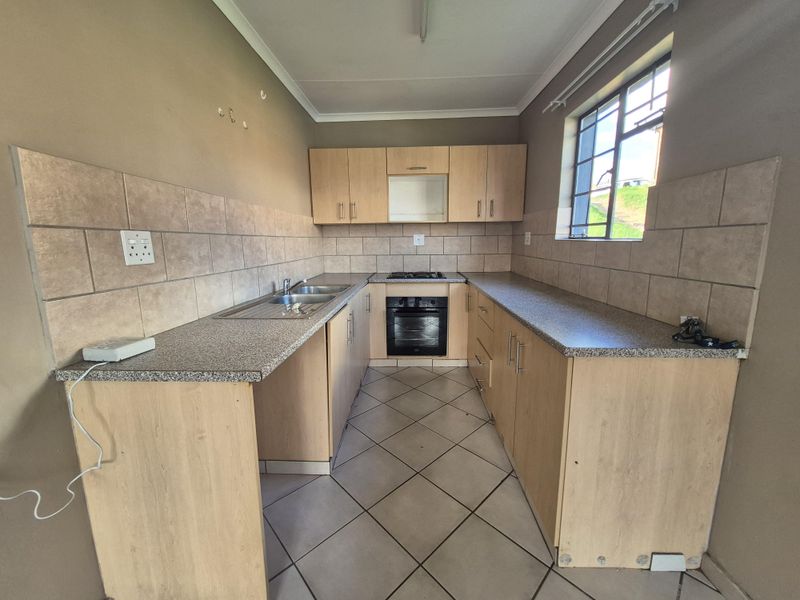 A functional kitchen featuring light wood cabinetry, granite-look laminate countertops, a built-in oven, gas hob, and tiled flooring.