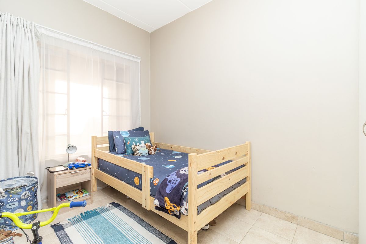 A functional bedroom featuring neutral wall finishes and tiled flooring, providing a clean and simple space suitable for various interior design styles.
