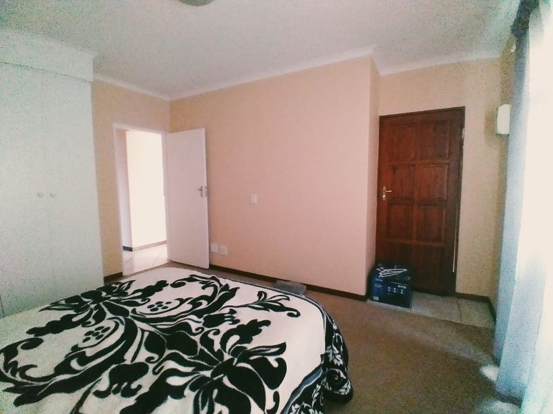 A bedroom featuring carpeted flooring, a built-in wardrobe, and a wooden door leading to an adjacent space.