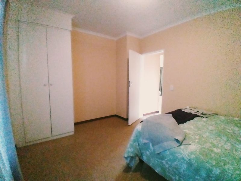 A bedroom featuring neutral walls, carpet flooring, and a built-in wardrobe with access to an adjoining room.