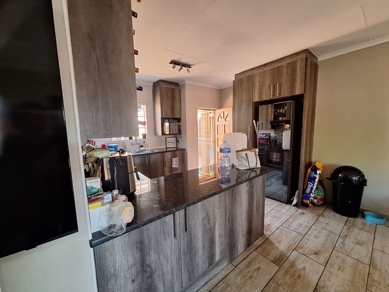 A functional kitchen featuring wood-look cabinetry, granite countertops, a breakfast bar, and tiled flooring, providing a practical layout for daily meal preparation.