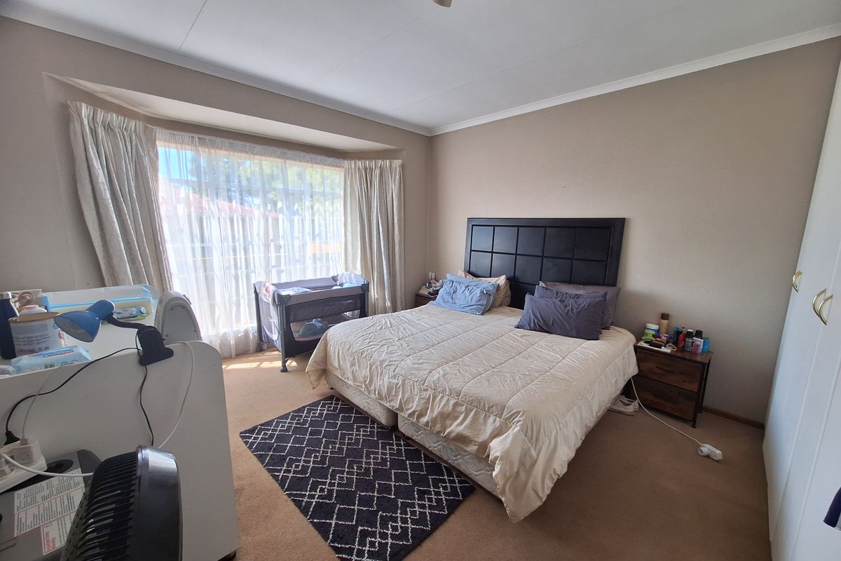Spacious bedroom featuring a large bay window, neutral wall tones, and built-in cupboard storage.