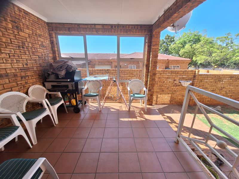 A covered patio area featuring exposed brick walls and tiled flooring, providing a functional outdoor space for relaxation and entertainment.