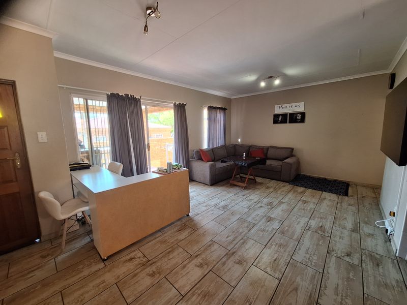 Spacious living room featuring wood-look tiled flooring, sliding glass doors leading to the patio, and neutral wall finishes.