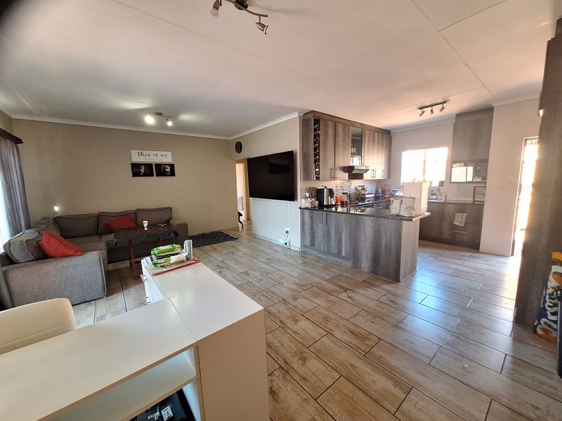 Spacious open-plan living area featuring tiled floors, a modern kitchen with granite countertops, and integrated cabinetry, creating a functional and cohesive living space.