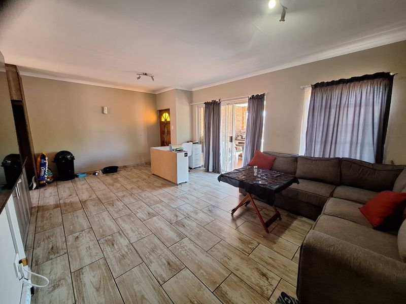 Spacious living area featuring wood-look tiled flooring, coved ceilings, and large sliding glass doors providing access to the outdoor patio area.