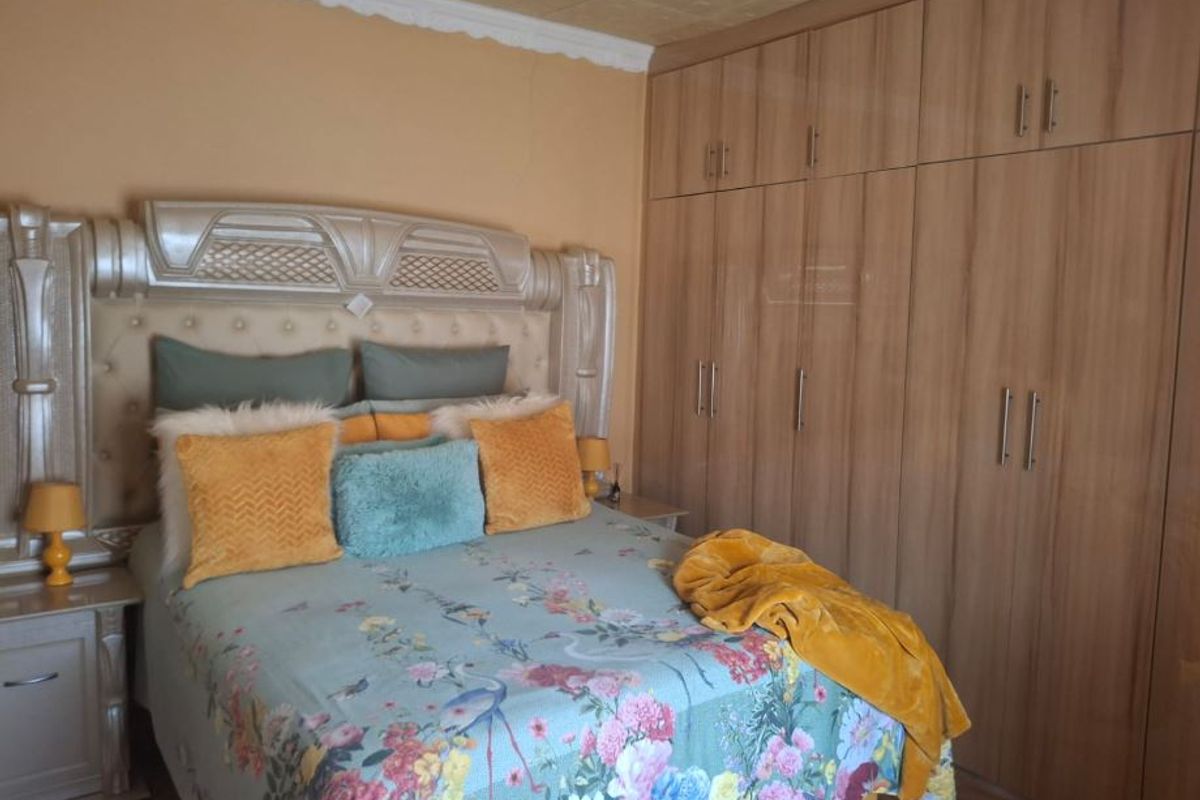 A bedroom featuring extensive built-in wooden cupboards, crown molding, and laminate flooring.