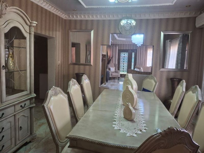 Formal dining room featuring decorative crown molding, tiled flooring, and built-in wall mirrors, providing a classic and structured space for entertaining.