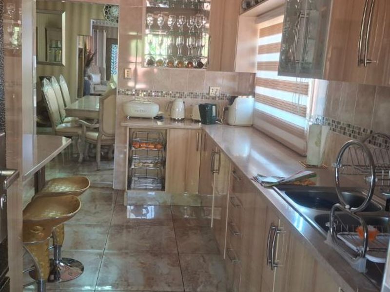 A functional kitchen featuring built-in cabinetry, tiled surfaces, and a breakfast bar area, with a view through to the adjacent dining room.