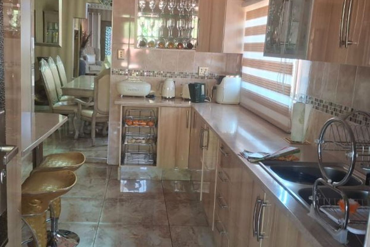 A functional kitchen featuring built-in cabinetry, tiled surfaces, and a breakfast bar area, with a view through to the adjacent dining room.