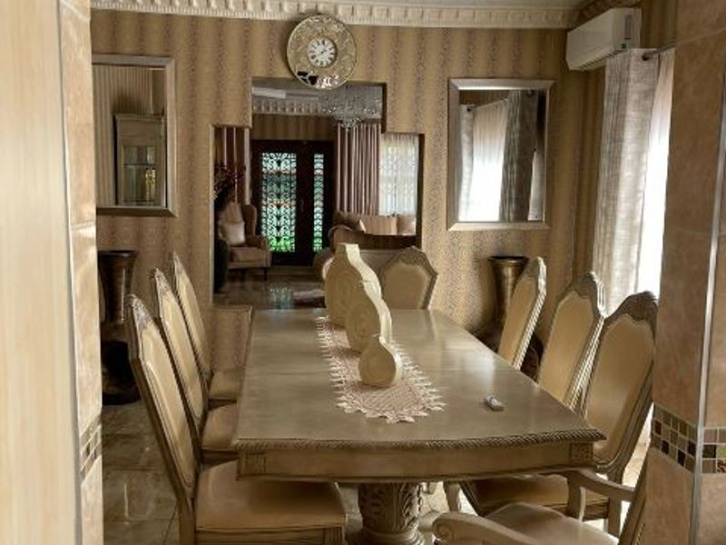 Formal dining room featuring decorative coffered ceilings, crown molding, tiled flooring, and a wall-mounted air conditioning unit.