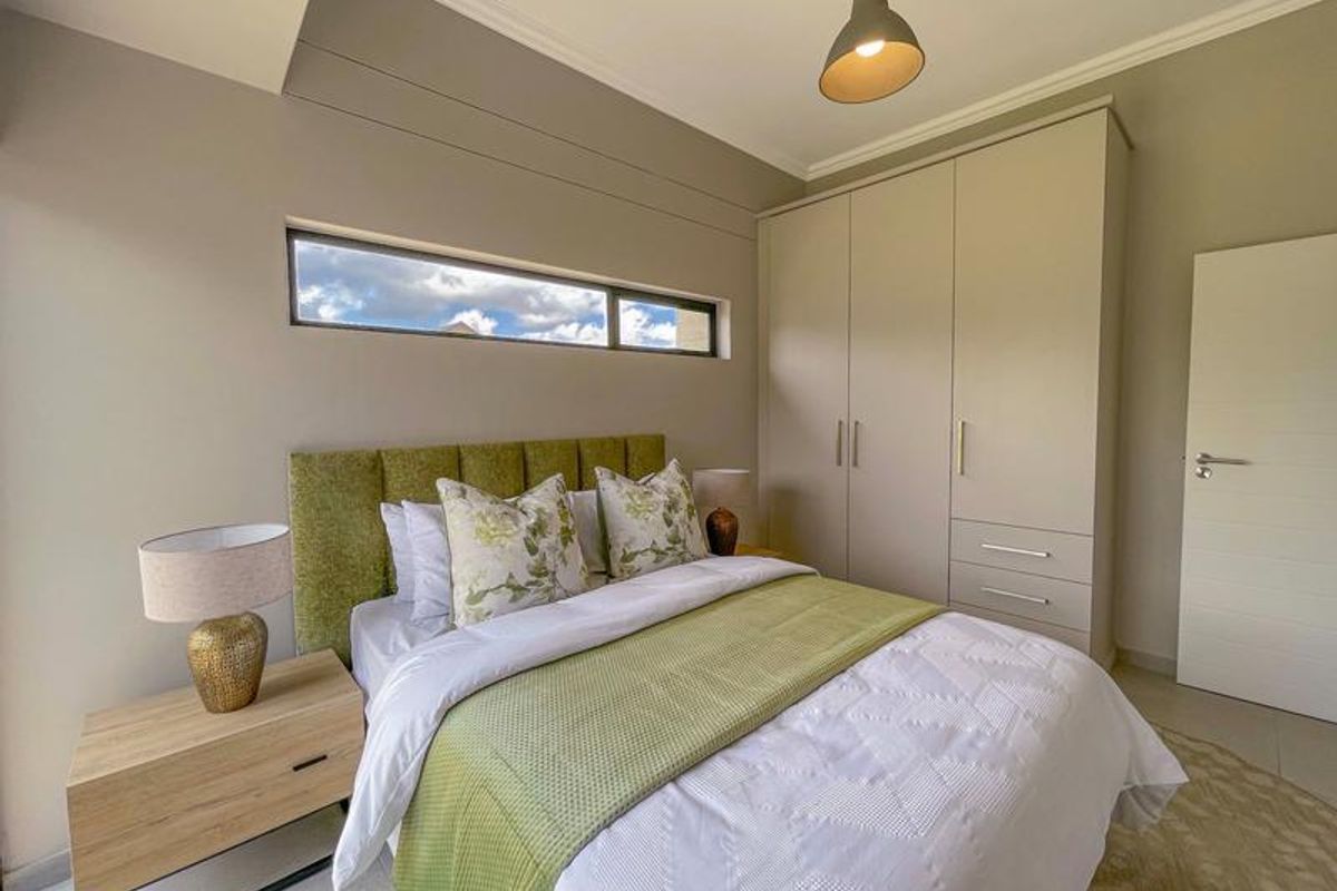 A well-maintained bedroom featuring built-in wardrobes, a horizontal clerestory window, and neutral wall finishes.