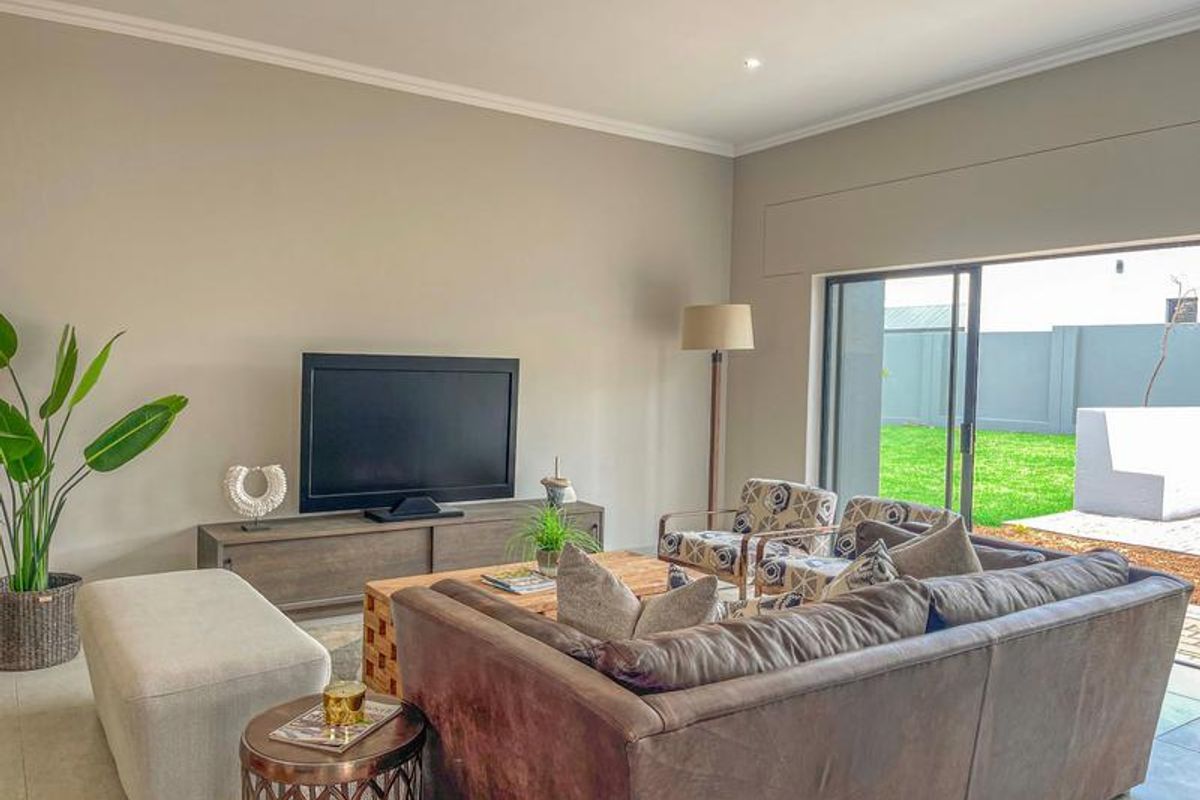 A bright and spacious living room featuring large sliding glass doors that provide seamless access to the rear garden and patio area.