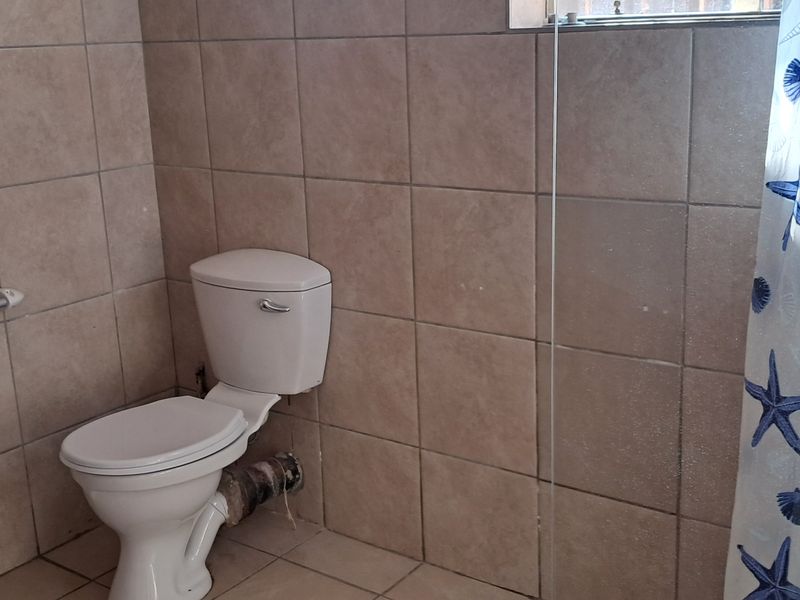 A functional bathroom featuring tiled walls, a standard toilet, and a shower area with a glass partition.