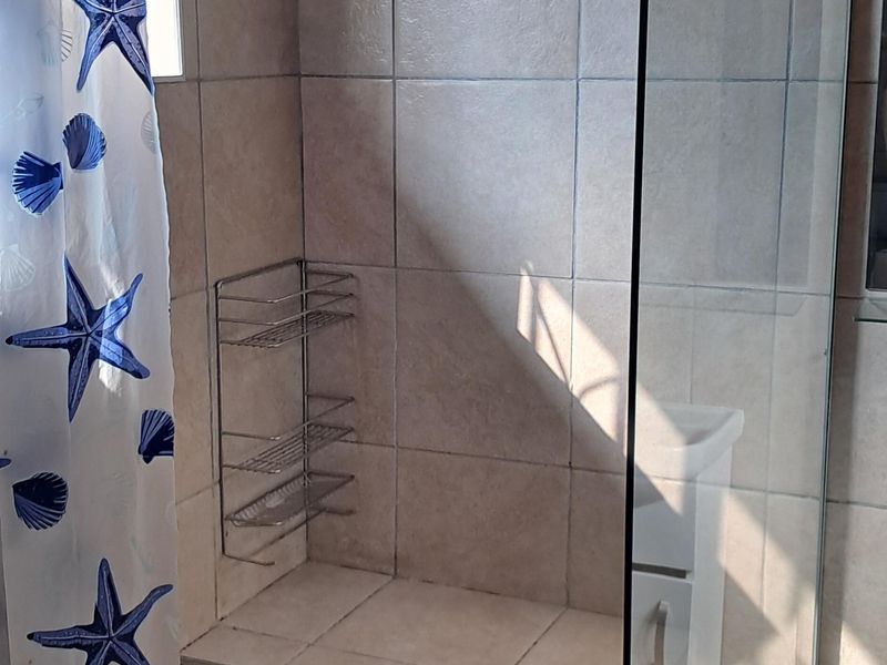 A tiled walk-in shower featuring a built-in tiled bench, glass screen, and overhead shower fixture.