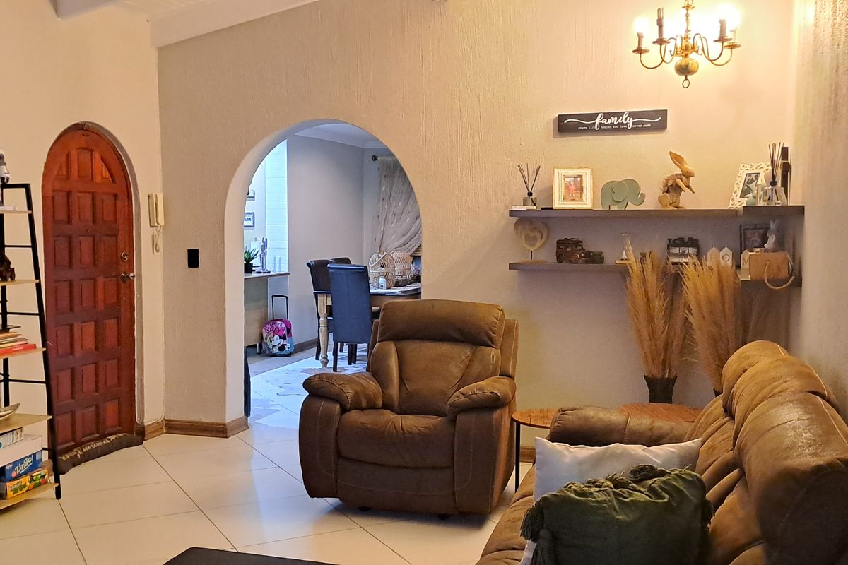 A cozy living room featuring arched doorways, tiled flooring, and built-in wall shelving, creating a warm and inviting atmosphere.