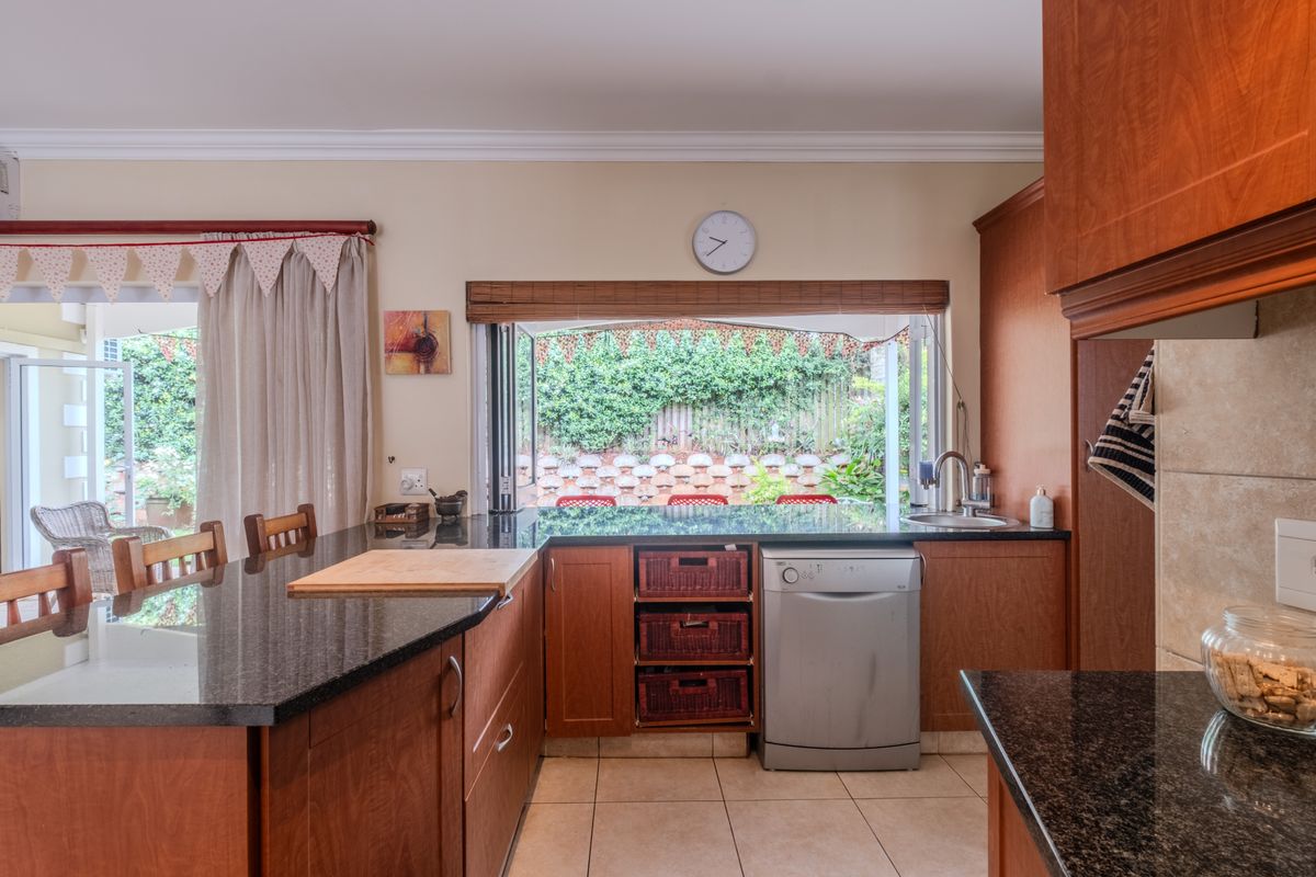 Kitchen featuring granite countertops, wooden cabinetry, and a convenient pass-through window overlooking the garden area.