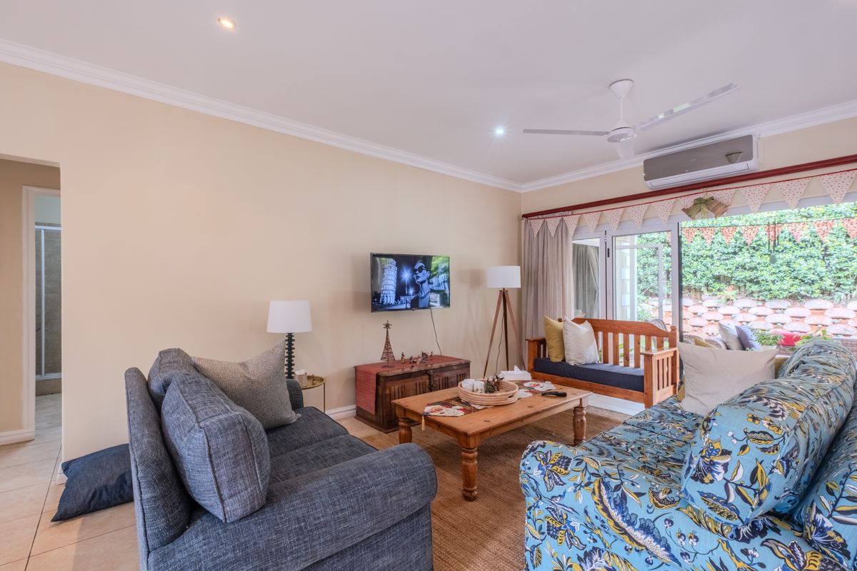 A comfortable living room featuring tiled flooring, a ceiling fan, split-system air conditioning, and large sliding glass doors providing access to the outdoor area.