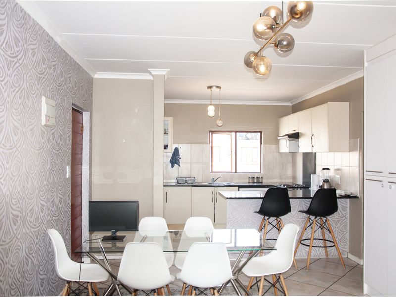Open-plan living and dining area featuring a modern kitchen with built-in cabinetry, a breakfast island, and tiled flooring throughout.