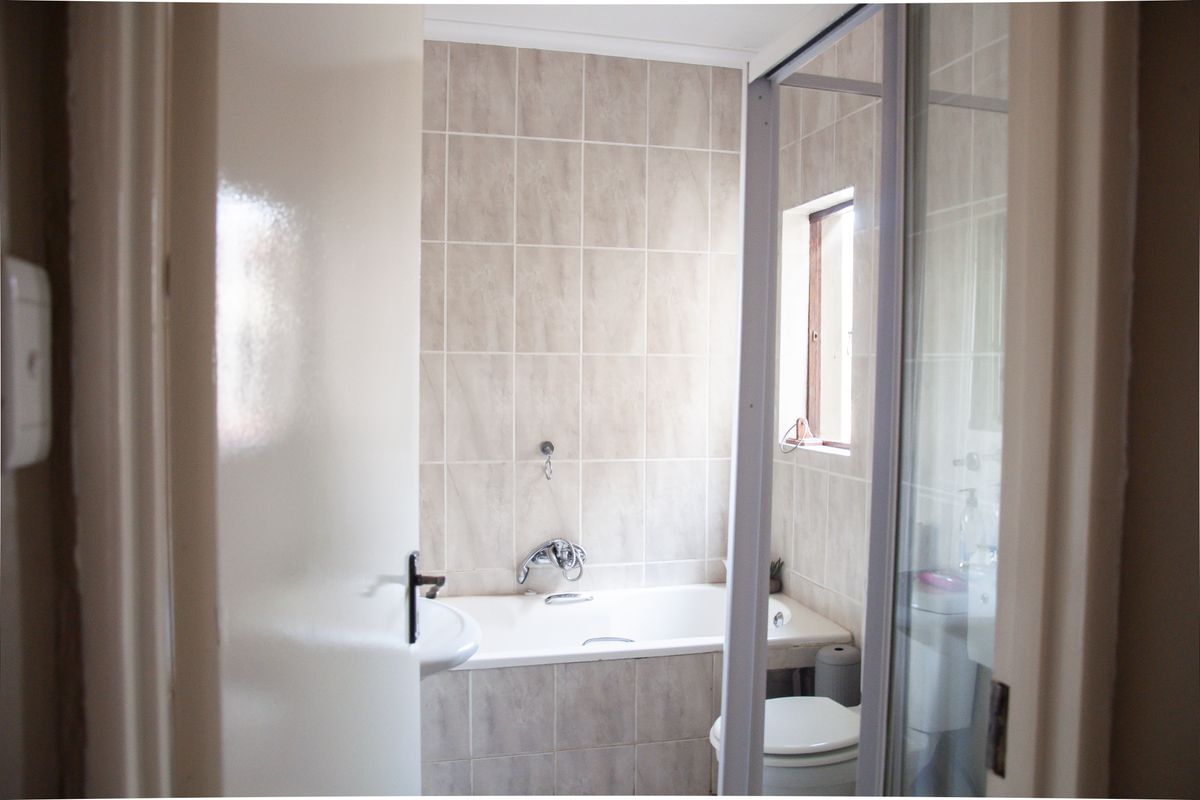 A functional bathroom featuring a built-in bathtub, tiled walls, a separate shower enclosure, and standard sanitary fixtures.