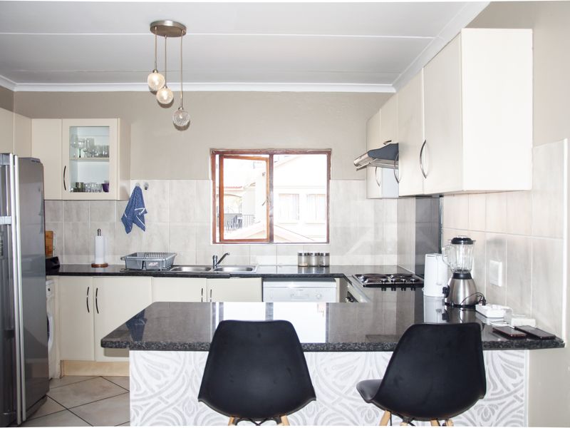 Functional kitchen featuring granite countertops, built-in cabinetry, a breakfast bar, and a tiled backsplash, offering a practical layout for daily cooking and dining.
