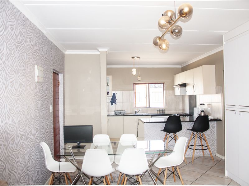 Open-plan living and kitchen area featuring tiled floors, modern cabinetry, a breakfast island, and decorative wallpaper, creating a functional and cohesive living space.