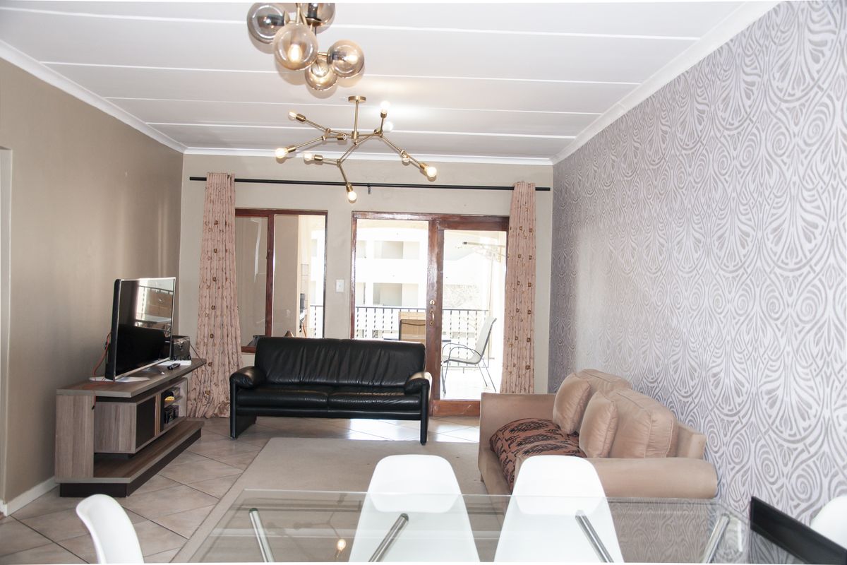 A living room featuring tiled flooring, patterned wallpaper, and a sliding glass door leading to an outdoor balcony area.