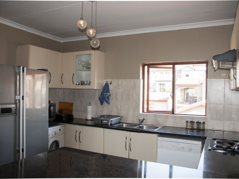 A functional kitchen featuring granite countertops, tiled backsplash, built-in cabinetry, and integrated appliances including a hob and extractor fan.