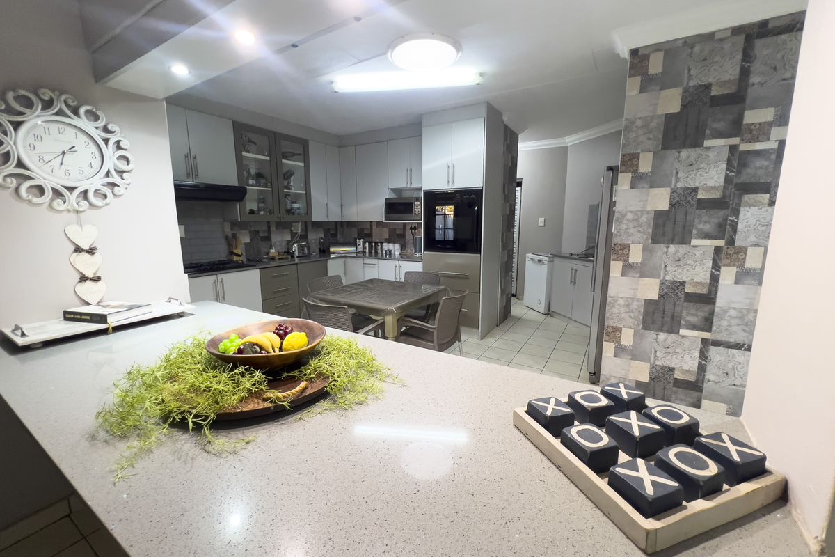 A well-appointed kitchen featuring quartz countertops, built-in oven and microwave, and ample cabinetry, flowing into an adjacent dining area.