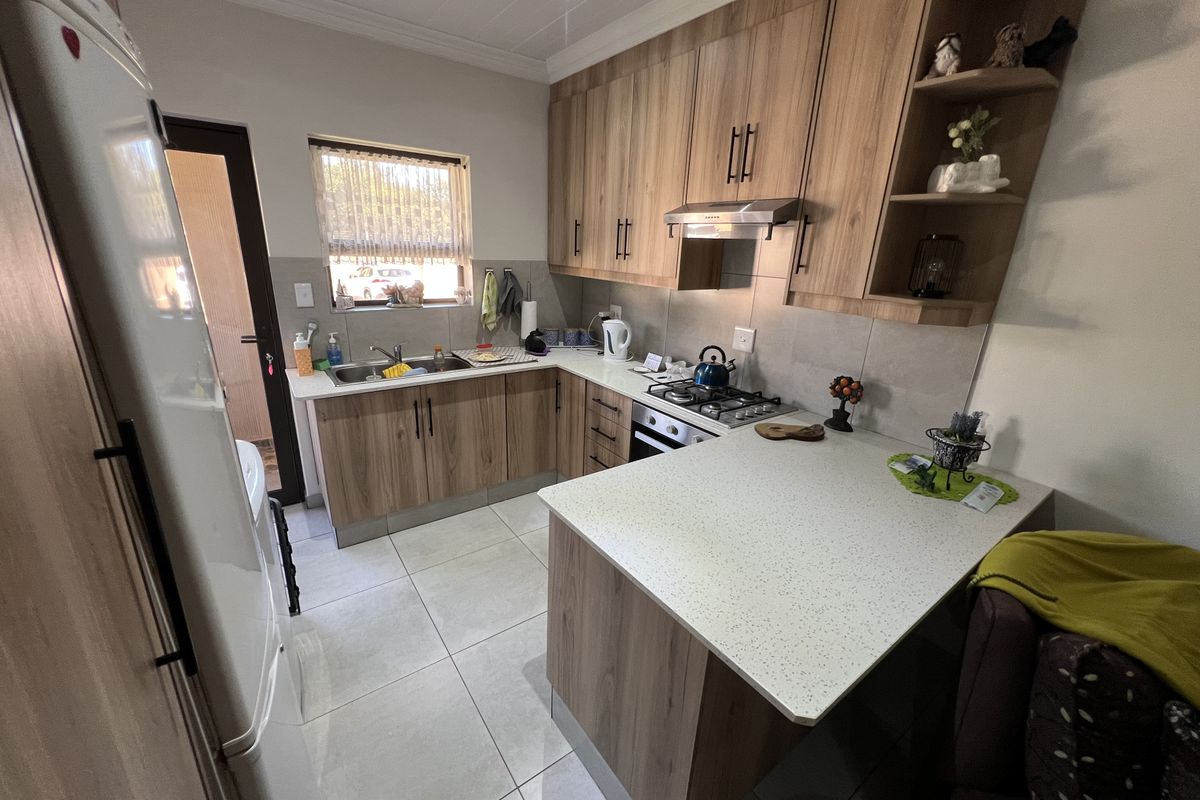 Modern kitchen featuring wood-look cabinetry, stone-style countertops, a built-in gas hob with extractor fan, and tiled flooring.